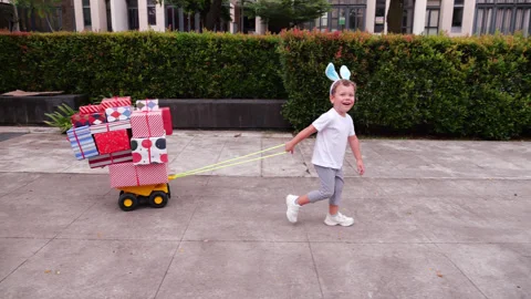 Enthusiastic child pulling cart loaded with gifts in a residential area Stock Footage 301000232