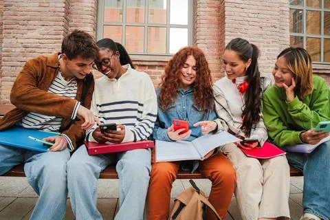 Enthusiastic group of students sharing ideas and laughter while using mobil.. Stock Photos