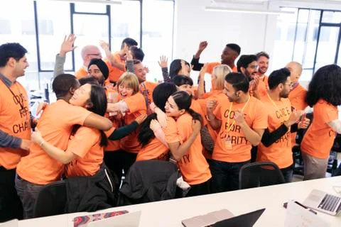 Enthusiastic hackers celebrating, coding for charity at hackathon Foto stock