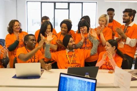 Enthusiastic hackers celebrating, coding for charity at hackathon Stock Photos