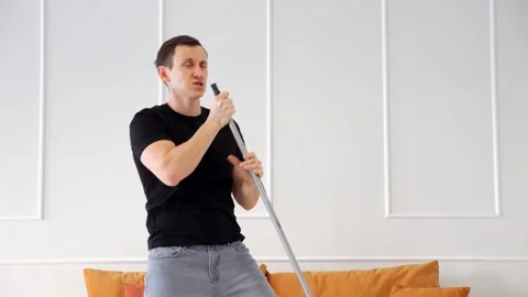 Enthusiastic man singing with mop as microphone Stock-Footage 307738929