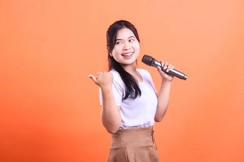 Enthusiastic singer with a microphone points to the side. Stock Photos