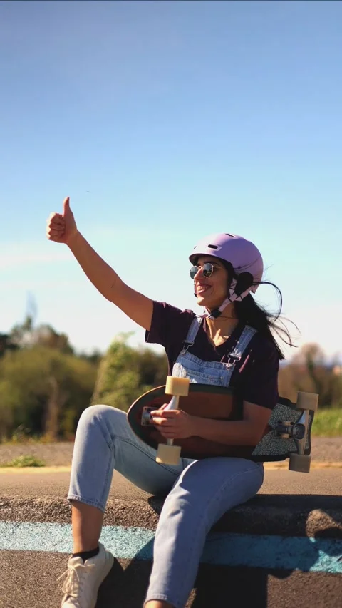 Enthusiastic skater giving thumbs up while sitting on a curb vertical Stock Footage 308742876