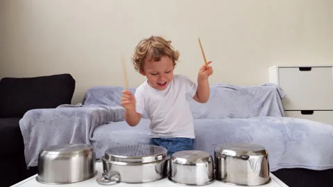 Enthusiastic toddler playing drums with kitchen pots and wooden sticks Video stock 310528273