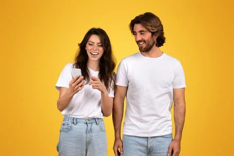 Enthusiastic young couple collaboratively using a laptop computer, showing Stock Photos