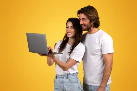 Enthusiastic young couple collaboratively using a laptop computer, showing Stock Photos