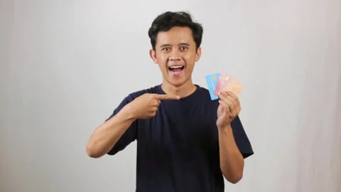 Enthusiastic young man presenting credit cards with a confident smile Stock Footage 318453675