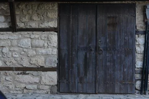 Entrance of building with old wooden doors in stone wall outdoors Stock Photos