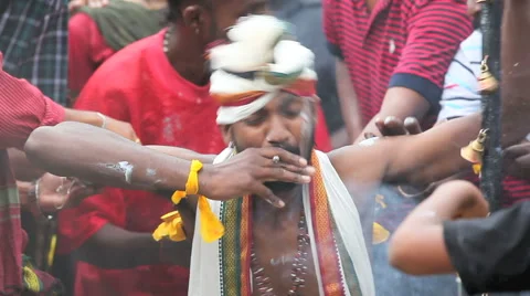An entranced devotee smokes a cigar while having his back pierced with hooks Stock Footage 41675654