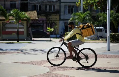  ENTREGADOR - COMIDA - BICICLETA Jovem com uma mochila entregando comida e... Stock Photos