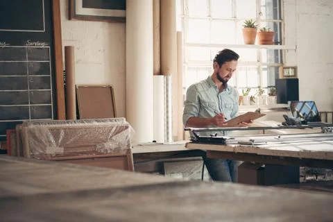 Entrepreneur in his workshop checking figures on a clipboard Stock Photos