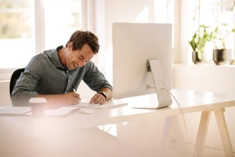 Entrepreneur making notes while working on computer at home 스톡 사진