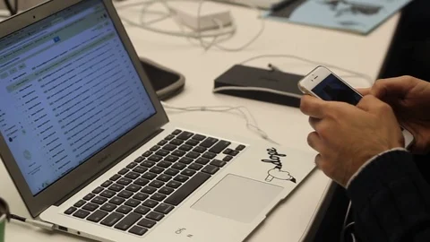 Entrepreneur using his cellphone &amp; checking email on laptop computer Video stock 76318460