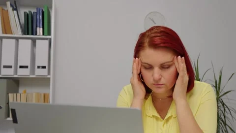 Entrepreneur using laptop writing notes at home office desk tired of working Stock Footage 296590495