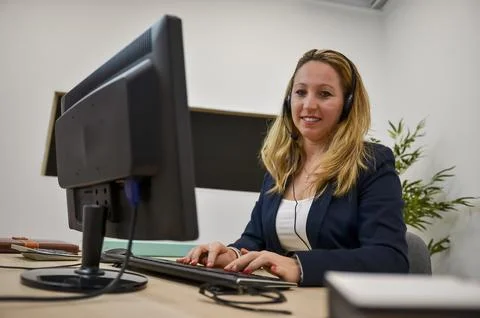 Entrepreneur working from office using headset and desktop computer Stock Photos