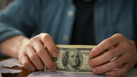 Entrepreneurs hands grip a thick stack of dollar bills on his office desk sh Stock Footage 338186599