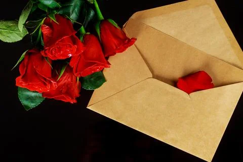 Envelope and bouquet of red roses on black table. Valentines day. Stock Photos