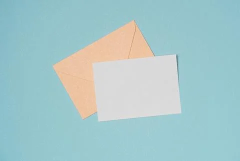 Envelope and empty white paper list on turquoise background from above. Copy  Stock Photos