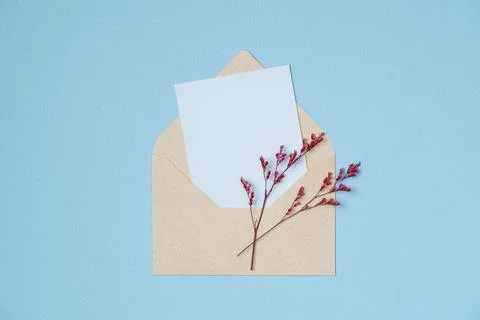 Envelope and empty white paper list with flowers on blue background from abov Stock Photos