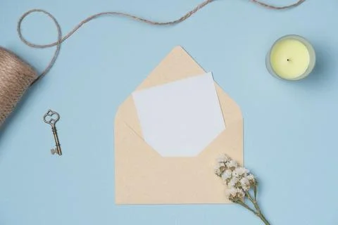 Envelope and empty white paper list with flower, string, candle, key on blue  Stock Photos