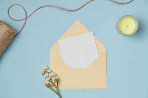 Envelope and empty white paper list, flower, string, candle on blue backgroun Stock Photos