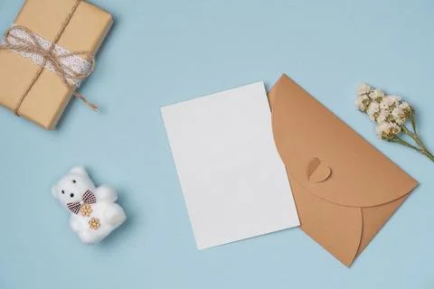 Envelope and empty white paper list with flower, gift box , bear toy on blu.. Stock Photos