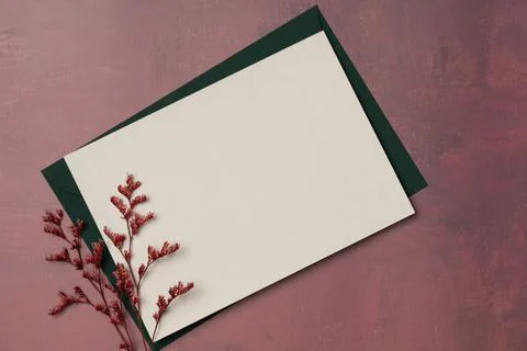 Envelope and empty white paper list on burgundy background from above. Space  Stock Photos