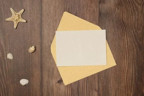 Envelope with blank paper and seashells on wooden background from above. Fl.. Stock Photos