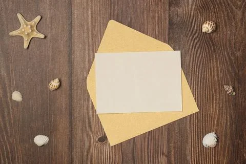 Envelope with blank paper and seashells on wooden background from above. Fl.. Stock Photos