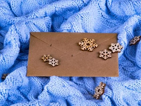 The envelope on the blue wool knitted background with the wooden snowflakes. Stock Photos