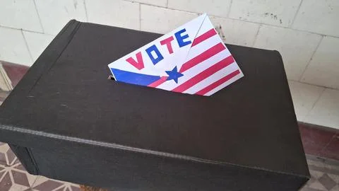 Envelope marked vote inserted into a black cardboard ballot box container Stock Photos