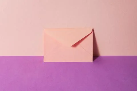 An envelope in a pink two-tone background. Stock Photos