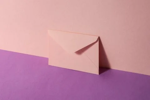 An envelope in a pink two-tone background. Stock Photos