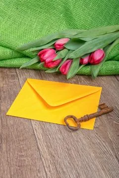 Envelope, rusty key and tulip on a wooden background 스톡 사진