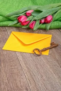 Envelope, rusty key and tulip on a wooden background Stock Photos
