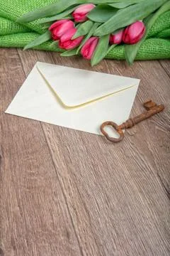 Envelope, rusty key and tulip on a wooden background 스톡 사진