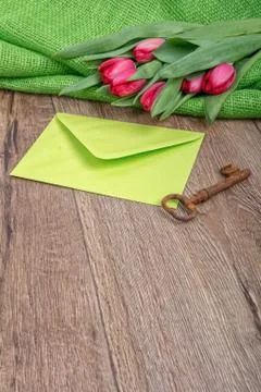 Envelope, rusty key and tulip on a wooden background Foto stock