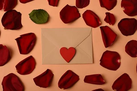 An envelope surrounded by rose petals and a heart. Symbol of love and romance Stock Photos
