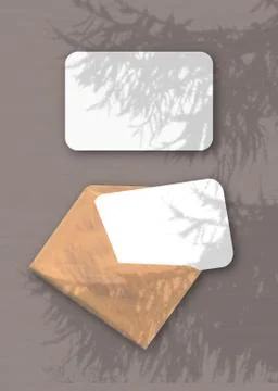 An envelope with two sheets of textured white paper on the brawn background o Stock Photos