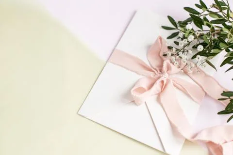 Envelope on a white-pink background with peach silk ribbon and pink flowers.  Stock Photos