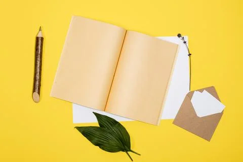 Envelope with white sheets, open notebook and pencil lie on a yellow backgrou Stock Photos