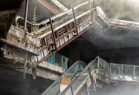 Enveloped in a ghostly haze, the skeletal, rust-eaten escalators rise throu.. Stock Photos