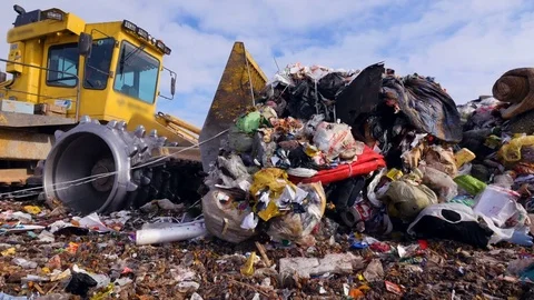 Enviromet pollution concept. A low angle view on a landfill compactor moving Stock Footage 81247444