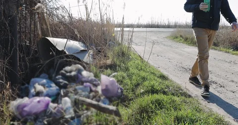 Environment, the guy throws out a plastic bottle. Rubbish on the side of the roa Stock Footage 106068311