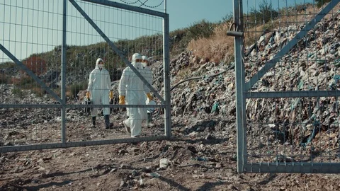 Environment pollution. Male scientists inspecting toxic garbage mountains at Stock Footage 113929140