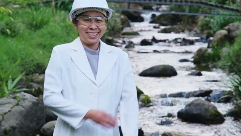 Environmental engineer stands with arms crossed on forest stream background Stock Footage 172390930