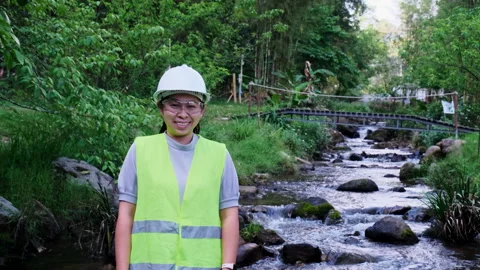 Environmental engineer stands with thumbs-up gesture on forest stream background Stock Footage 172390400