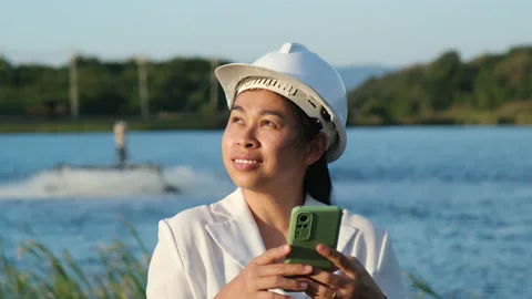 Environmental engineer uses a mobile phone to operate an oxygen turbine aerator. Stock Footage 229704568