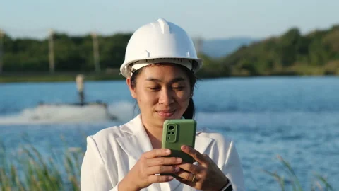Environmental engineer uses a mobile phone to operate an oxygen turbine aerator. Stock Footage 229704934