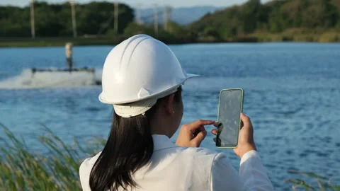 Environmental engineer uses a mobile phone to operate an oxygen turbine aerator. Stock Footage 229705447